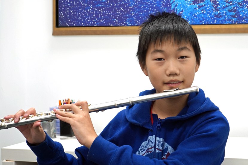 Boy playing the flute during his lesson