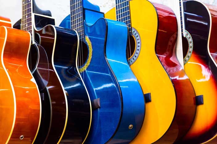 A colorful row of acoustic guitars in different sizes and finishes standing side by side