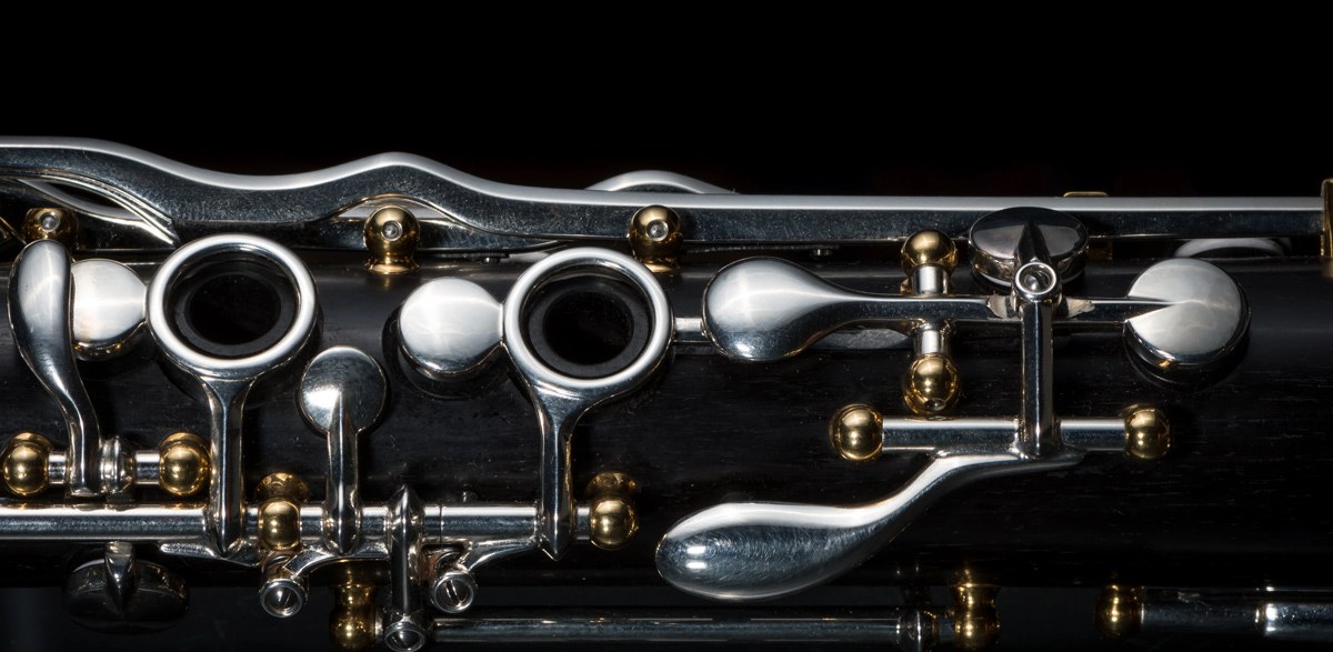 Close-up of a clarinet barrel and silver keys lit against a dark background