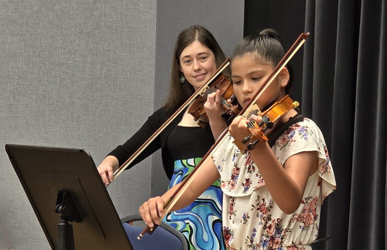 A violin teacher and student playing together during a lesson