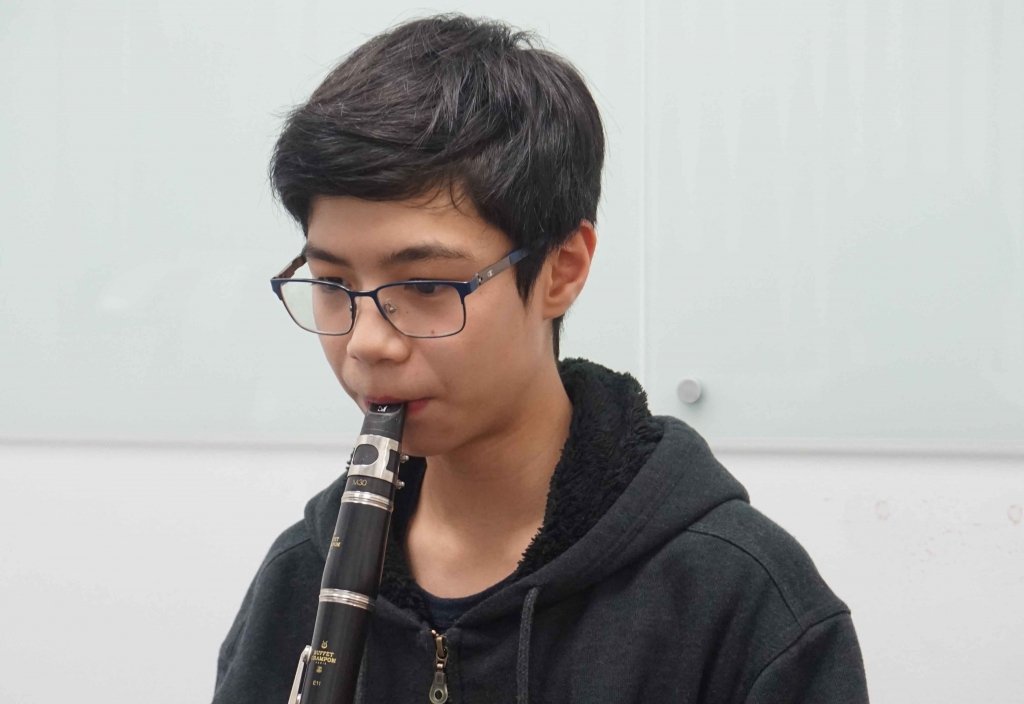 Teenage boy in glasses playing the clarinet during a lesson