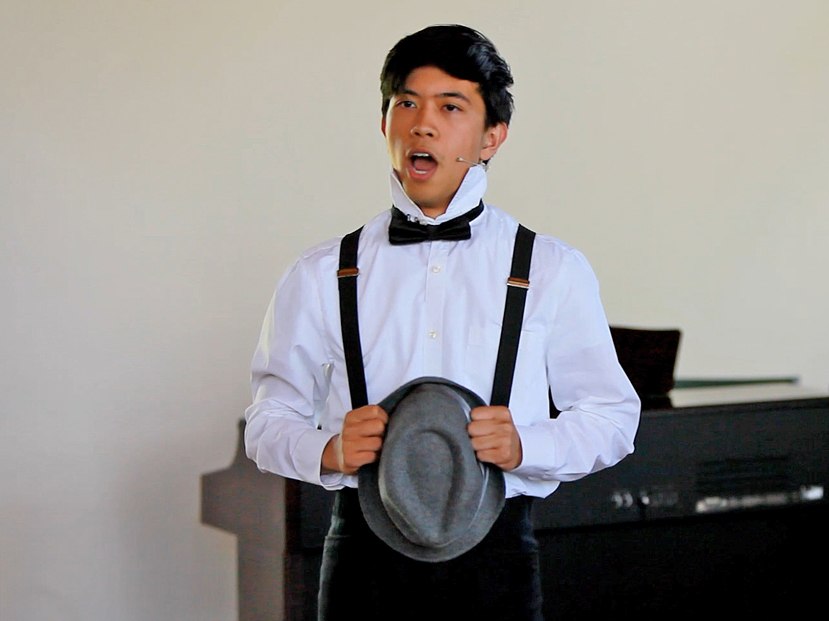 A teenage boy is performing a musical theatre song, confidently. His posture is dynamic, showing his passion and energy, and his stage presence is captivating.