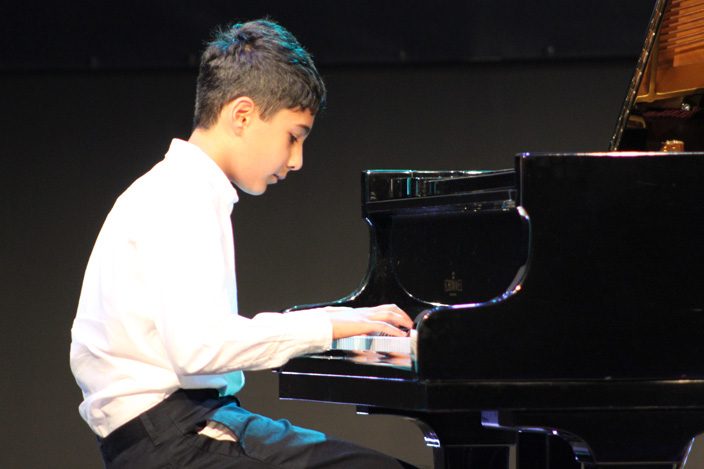 Teen boy performing at a piano recital