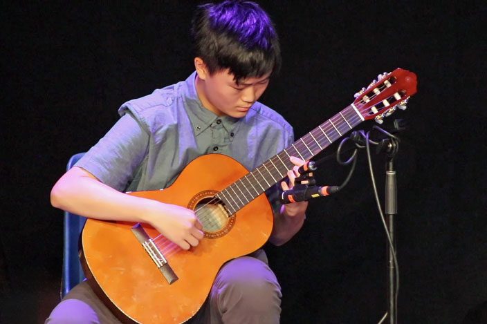 Teen playing classical guitar at a recital