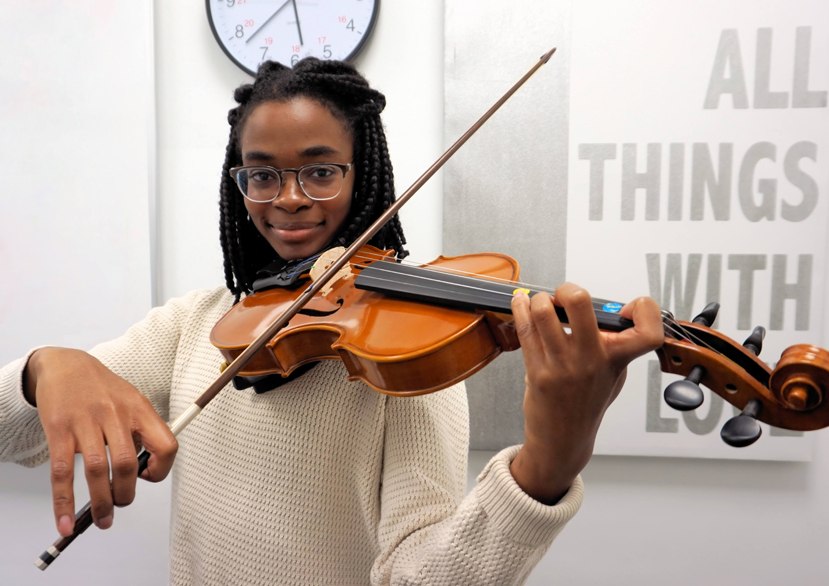 Teenage girl playing violin, looking directly ahead