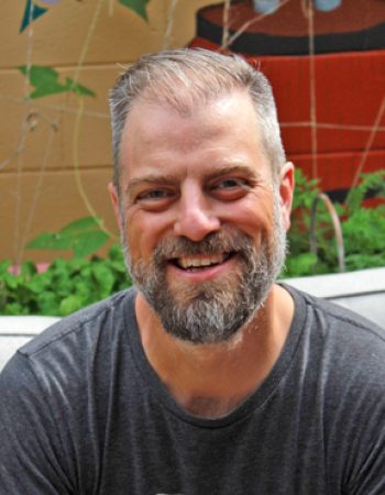 Portrait of a saxophone, flute, and clarinet teacher in Mississauga, sitting in a well-lit room. The teacher is smiling.